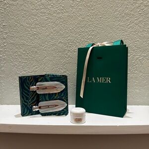 Two La Mer hair clips with logo green bag and mini moisturizer